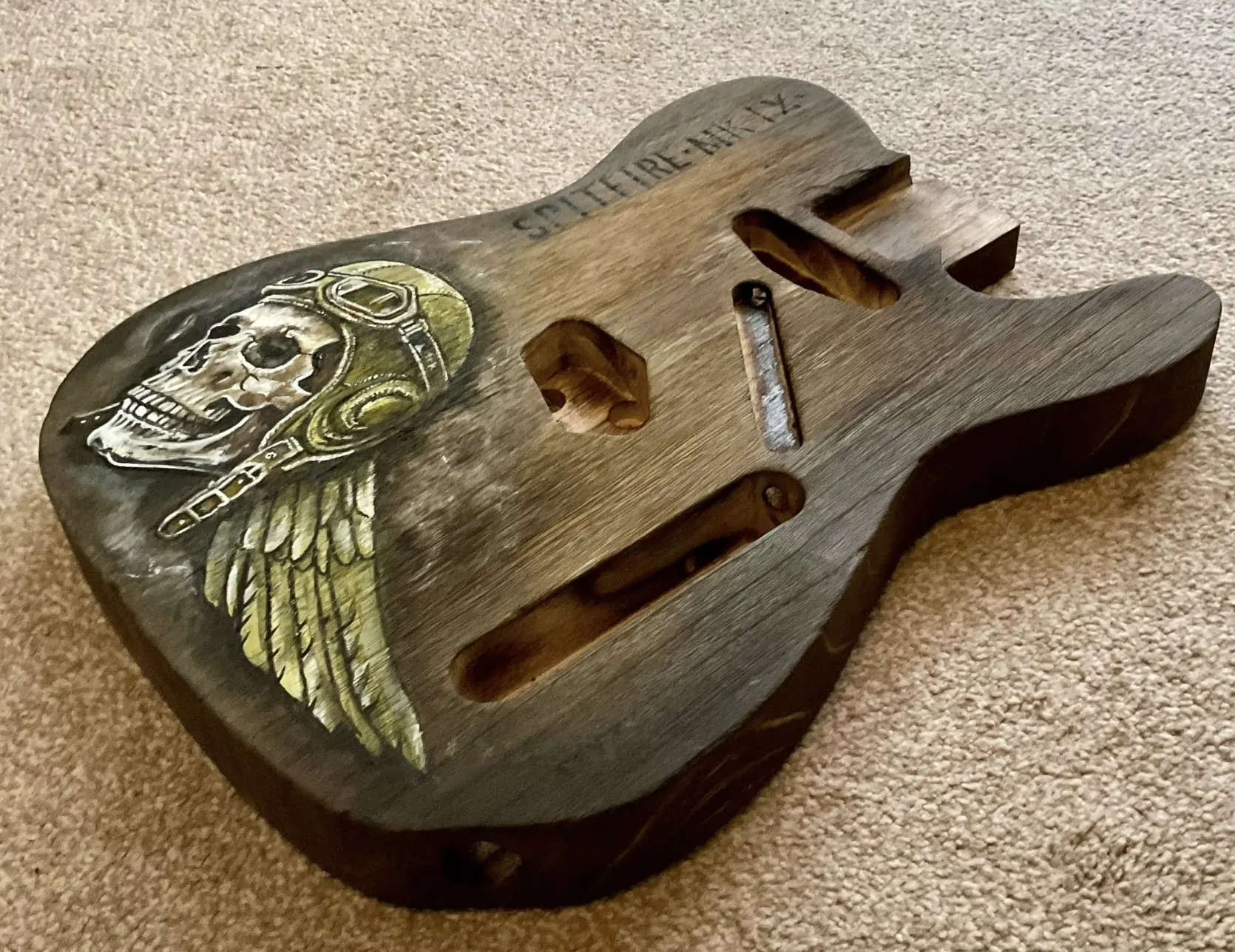 Close view of a carved guitar body, control routes and wood grain